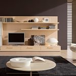 minimalist living room design with cream polished round plywood coffee table using steel leg on dim gray rug as well as beige lounge chair also wooden tv rack stand built in wall cabinets as well as p 938x49
