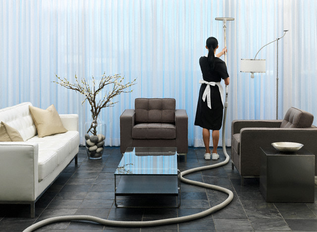 Maid vacuuming curtains --- Image by © Beau Lark/Corbis